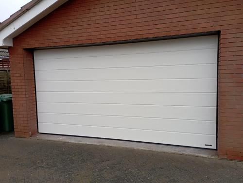 Double insulated sectional door with a medium rib design in white installed by henderson on the wirral