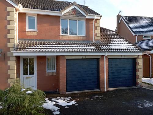 Insulated sectional garage door in a medium rib design in blue installed by henderson in Cheshire